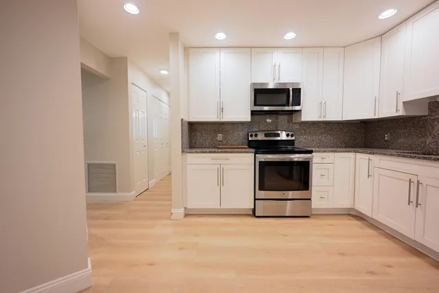 a kitchen with stainless steel appliances granite countertop a stove a sink and a microwave