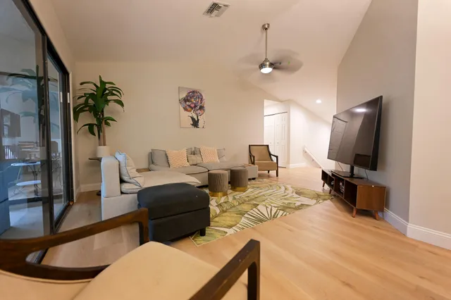 a living room with furniture a flat screen tv and a large window