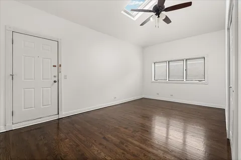 an empty room with wooden floor closet and windows