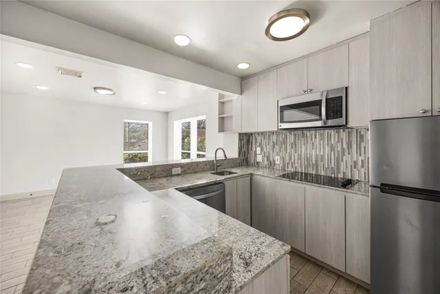 a kitchen with stainless steel appliances granite countertop a sink and a refrigerator