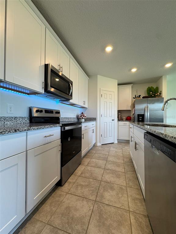 4836 Rigging Street Haines City, FL 33844 - Photo 7 of 29 a kitchen with stainless steel appliances granite countertop a sink and a stove