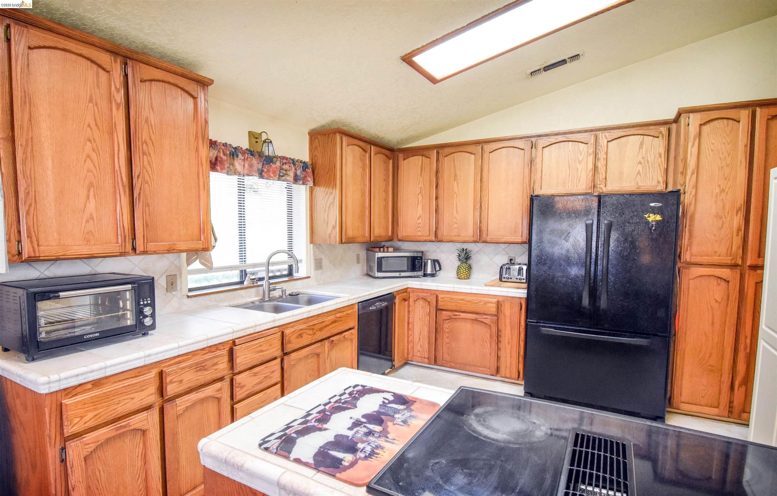 15170 Potato Ranch Road Sonora, CA 95370 - Photo 17 of 49 Kitchen with tile counters, black appliances, lofted ceiling, and backsplash
