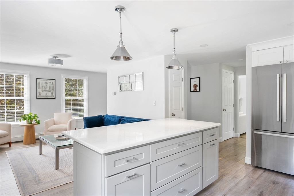 99 Doane Street Cohasset, MA 02025 - Photo 7 of 36 a kitchen with a refrigerator a sink dishwasher a dining table and chairs with wooden floor