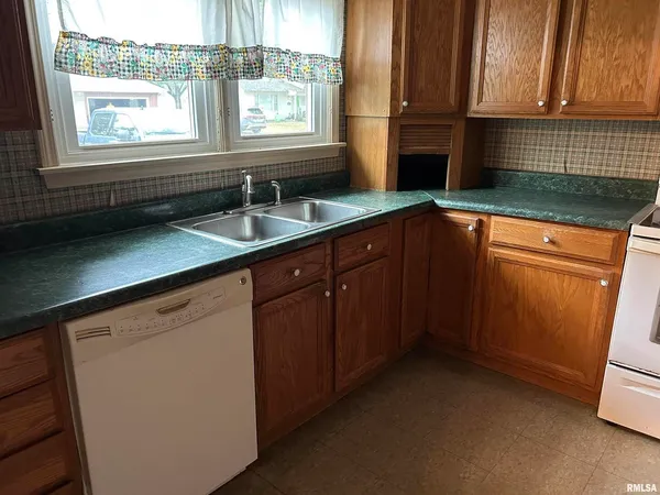 a kitchen with granite countertop a sink window and cabinets