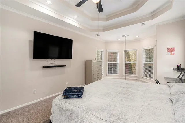 a bedroom with a bed a flat screen tv and a ceiling fan