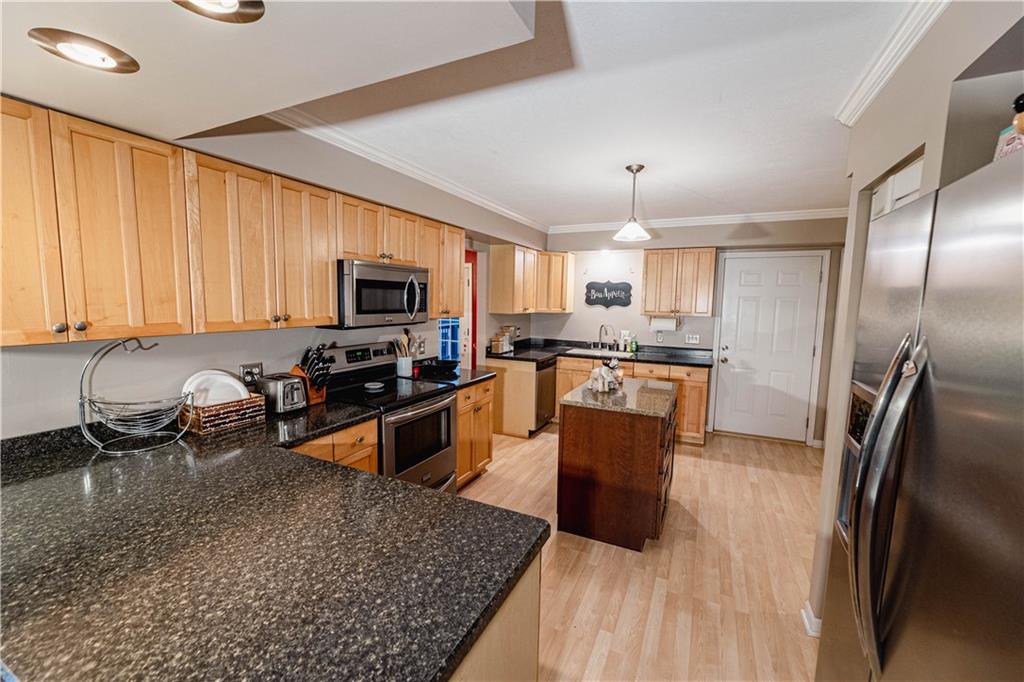3673 Mitchell Road New Castle, PA 16105 - Photo 9 of 25 a kitchen with stainless steel appliances granite countertop a stove top oven a sink dishwasher a dining table and chairs with wooden floor
