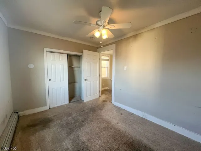 an empty room with a chandelier fan and windows
