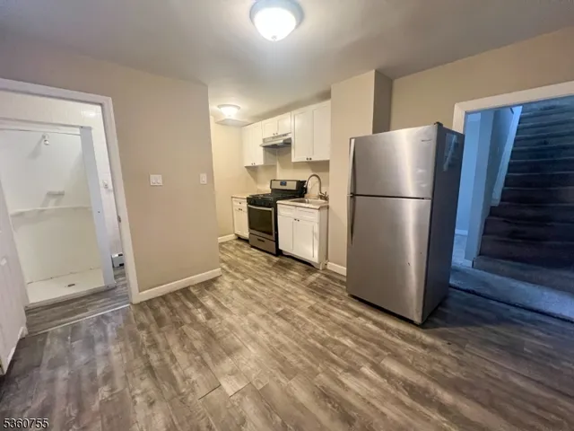 a view of a kitchen with refrigerator and wooden floor