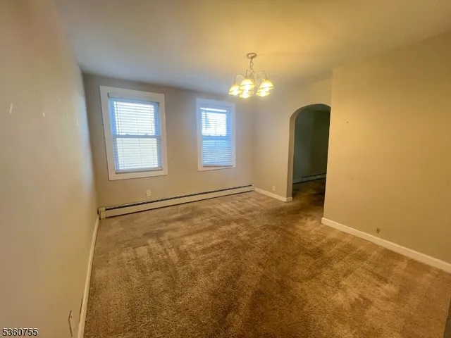 an empty room with chandelier fan and windows