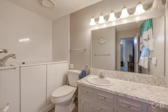 a bathroom with a granite countertop toilet a sink and a mirror
