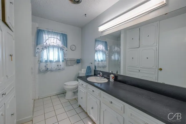 a spacious bathroom with a granite countertop sink a toilet and a mirror
