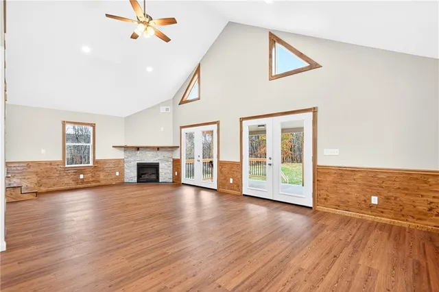 a view of an empty room with wooden floor fireplace and a window