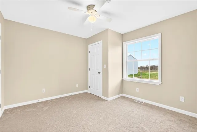 an empty room with a window and a fan