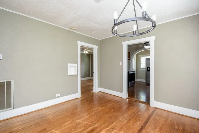 a view of empty room with wooden floor and chandelier