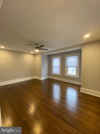 a view of empty room with wooden floor and fan