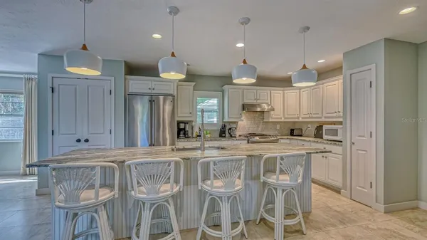 a kitchen with stainless steel appliances granite countertop a kitchen island a stove a cabinets a sink and a refrigerator