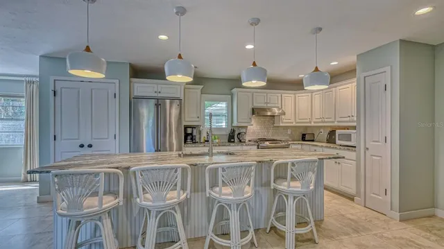 a kitchen with stainless steel appliances granite countertop a kitchen island a stove a cabinets a sink and a refrigerator