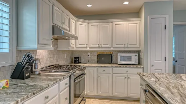 a kitchen with granite countertop a stove sink and cabinets