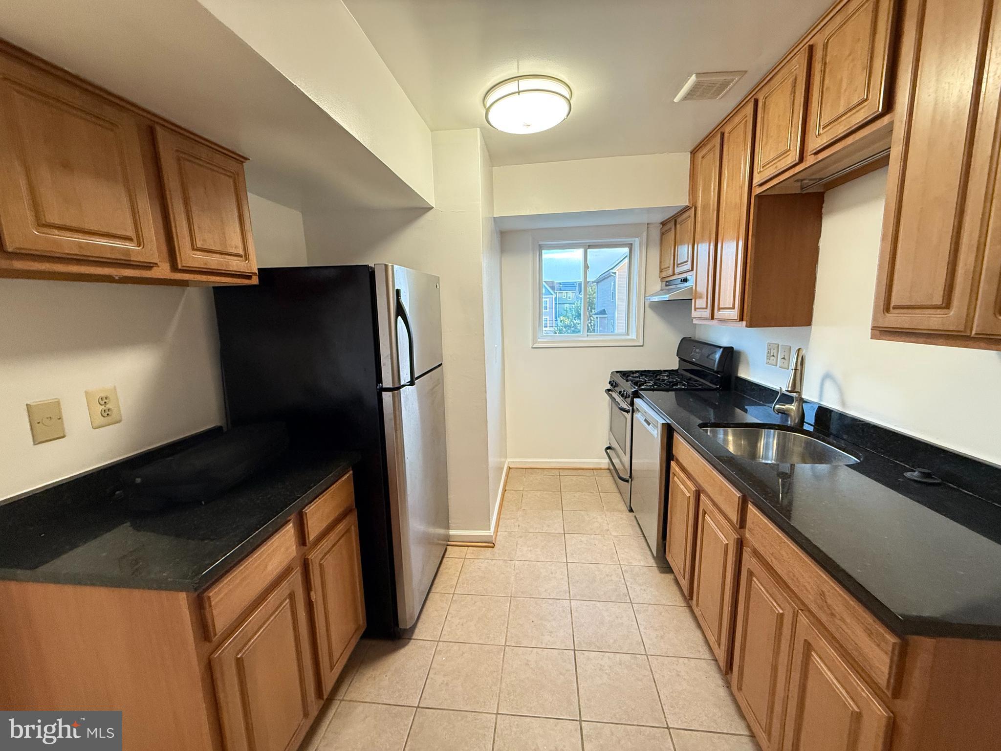 5009 D Street Southeast, Unit 303 Washington, DC 20019 - Photo 12 of 25 a kitchen with granite countertop a refrigerator a stove and a sink