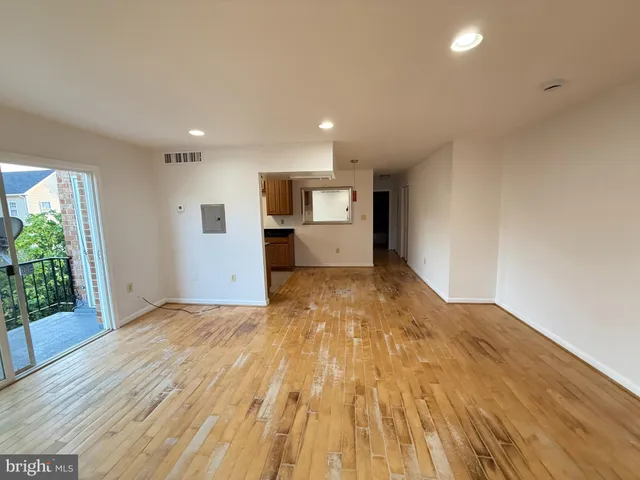 a view of an empty room with kitchen and a window