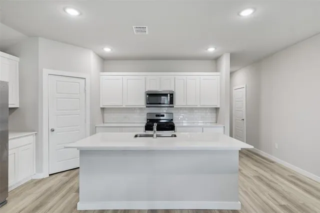 a kitchen with a refrigerator and a stove top oven