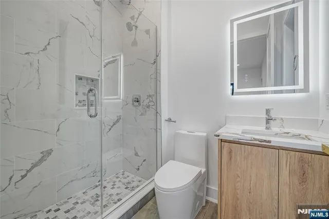 a bathroom with a granite countertop sink a toilet and shower