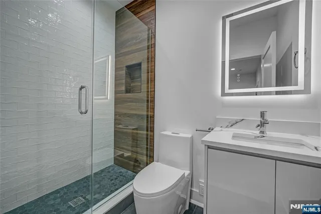 a bathroom with a granite countertop sink toilet a mirror and shower