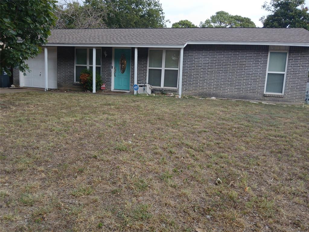 Single story home with brick siding, a front lawn, roof with shingles, and a garage