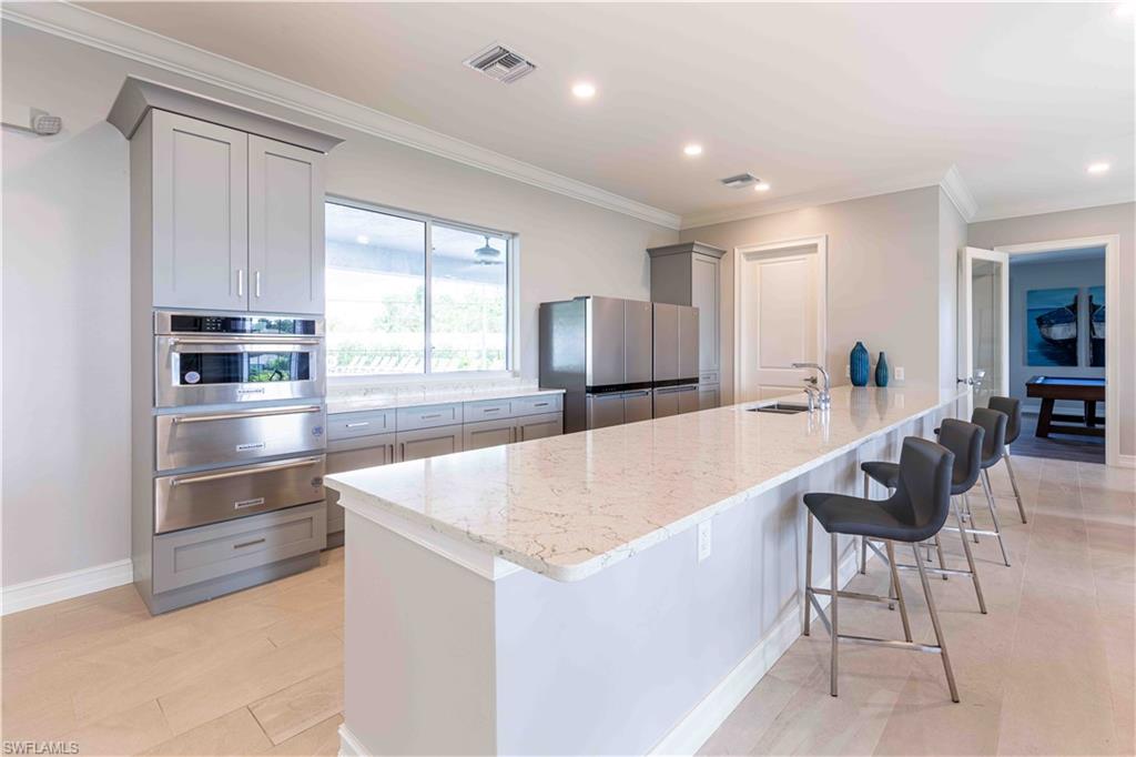 882 Enbrook Loop Naples, FL 34114 - Photo 16 of 19 a large kitchen with kitchen island a large counter top space a sink stainless steel appliances and cabinets