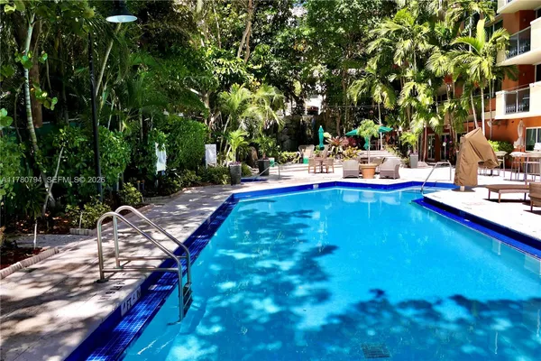 a view of swimming pool with lawn chairs under an umbrella