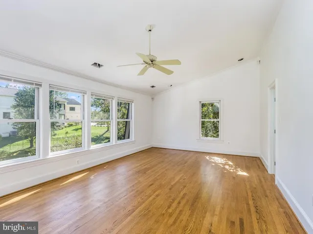 a view of an empty room with a window and wooden floor
