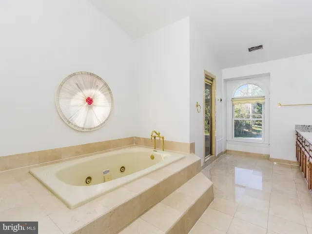 a white bath tub sitting in a spacious bathroom next to a window