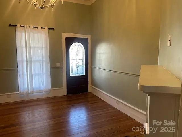 an empty room with wooden floor mirror and windows