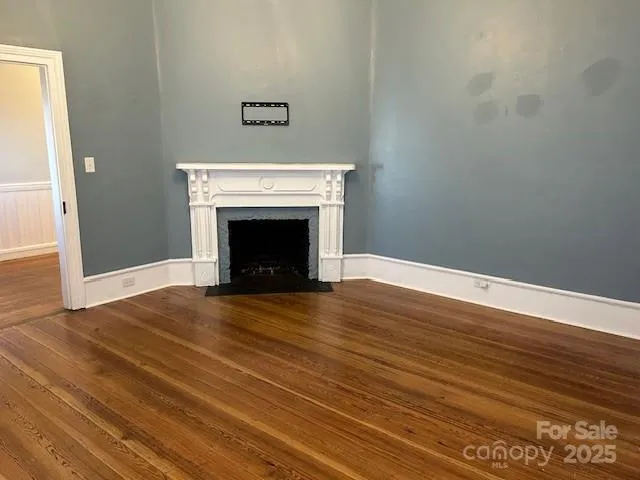 a view of an empty room with wooden floor and a fireplace