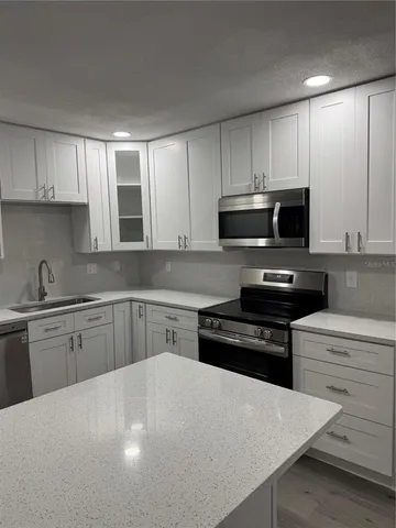 a kitchen with granite countertop a refrigerator sink and cabinets