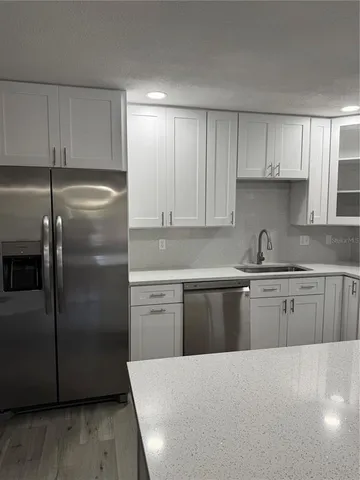 a white kitchen with granite countertop stainless steel appliances and white cabinets
