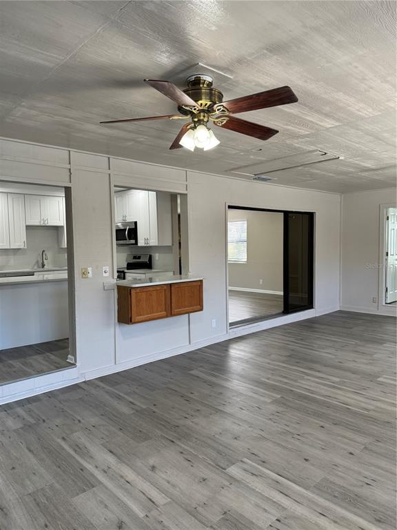 4550 Ewell Road Lakeland, FL 33811 - Photo 19 of 49 a view of an empty room with wooden floor and a kitchen
