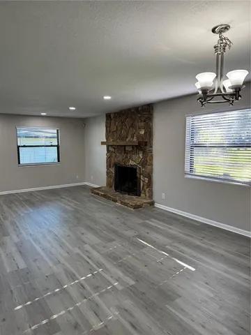 an empty room with wooden floor fireplace and windows