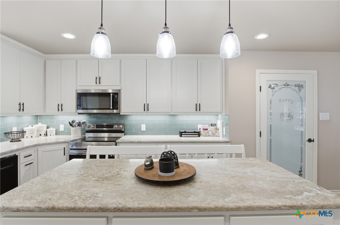 642 Phantom Rider Trail Spring Branch, TX 78070 - Photo 13 of 41 a kitchen with kitchen island granite countertop a sink cabinets and stainless steel appliances
