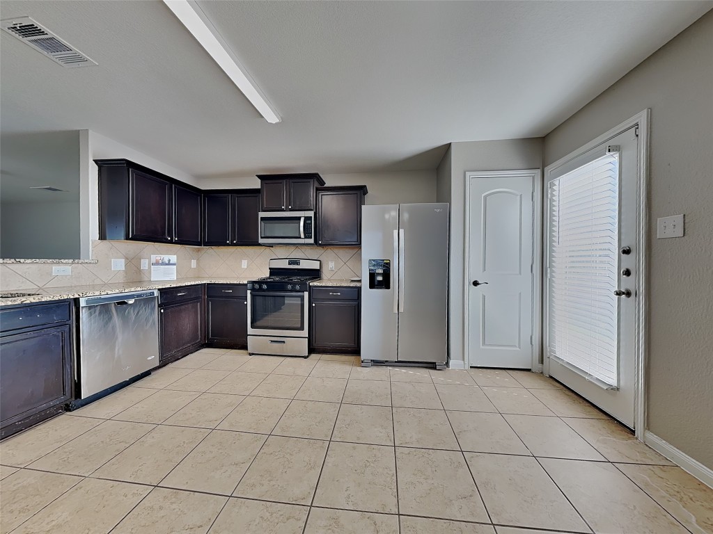 1525 Treeta Trail Kyle, TX 78640 - Photo 5 of 16 a kitchen with granite countertop a refrigerator and a sink