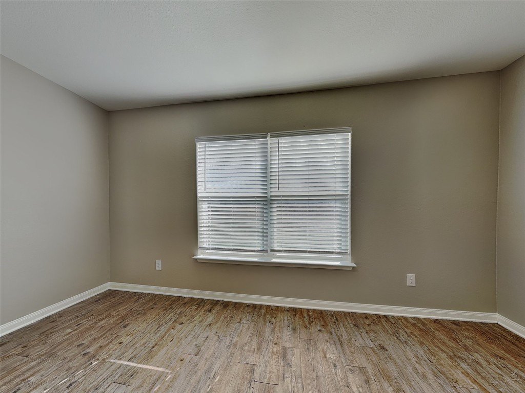 1525 Treeta Trail Kyle, TX 78640 - Photo 7 of 16 a view of an empty room with wooden floor and a window