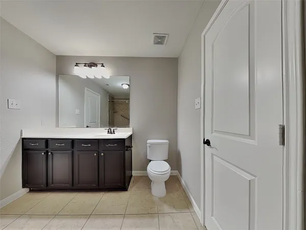 a spacious bathroom with a toilet a sink and mirror