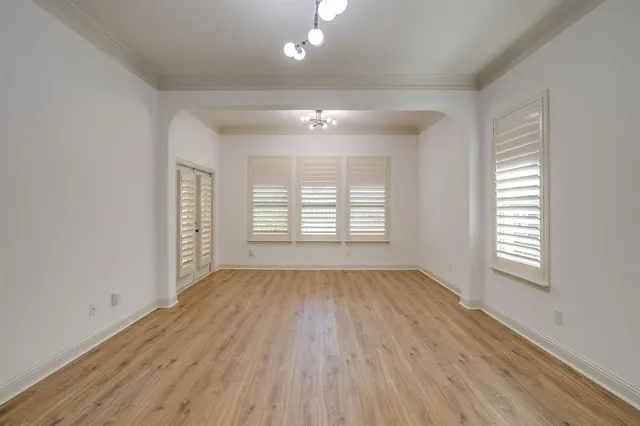an empty room with wooden floor cabinet and windows
