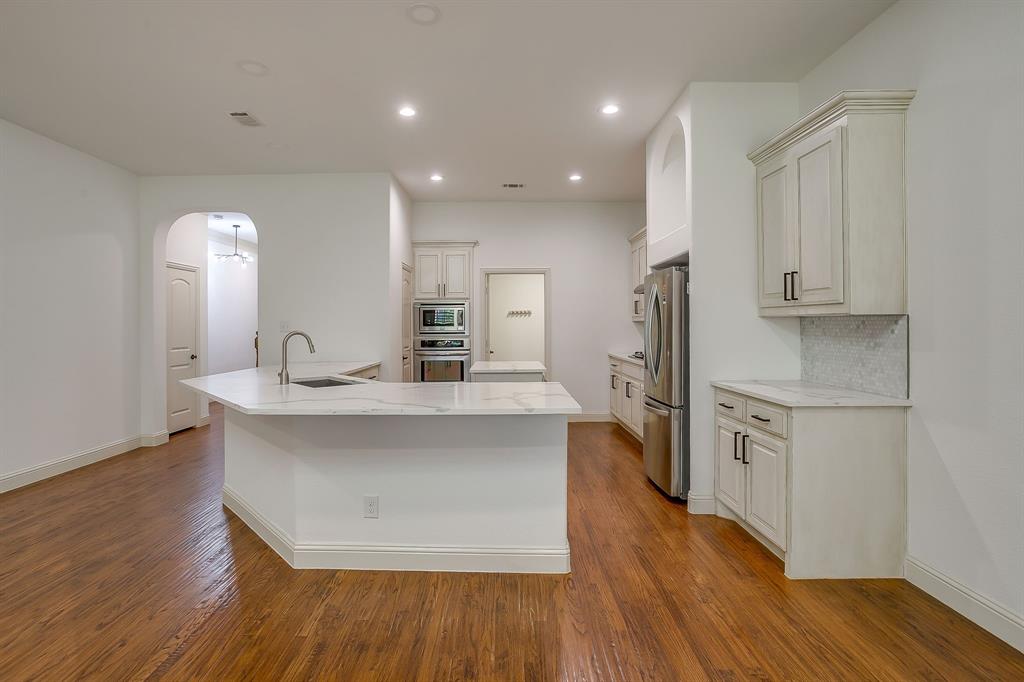 3009 Montebello Drive Denton, TX 76210 - Photo 9 of 38 a kitchen with stainless steel appliances a sink stove and wooden floor