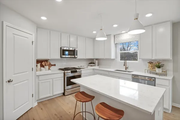 a kitchen with granite countertop white cabinets and stainless steel appliances