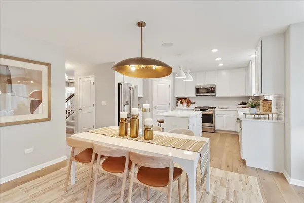a kitchen with stainless steel appliances kitchen island granite countertop a table chairs and a white cabinets