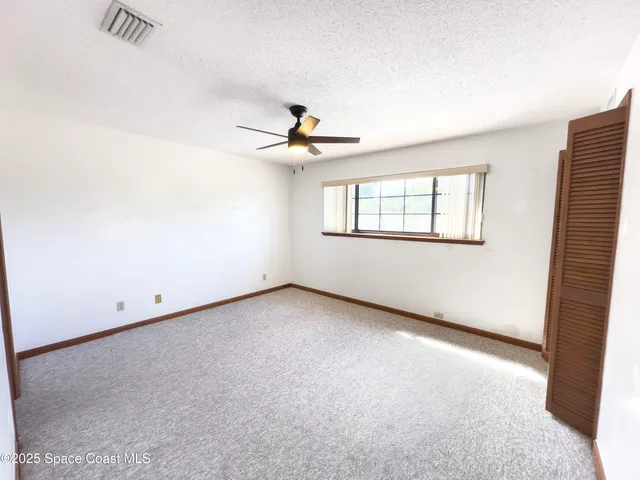 an empty room with windows and fan