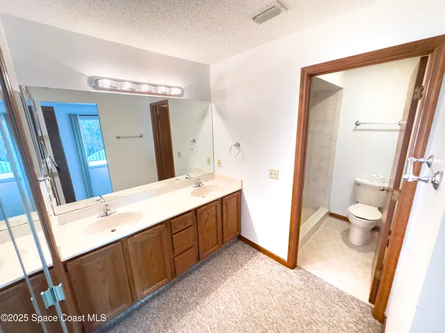 a spacious bathroom with a double vanity sink toilet and mirror