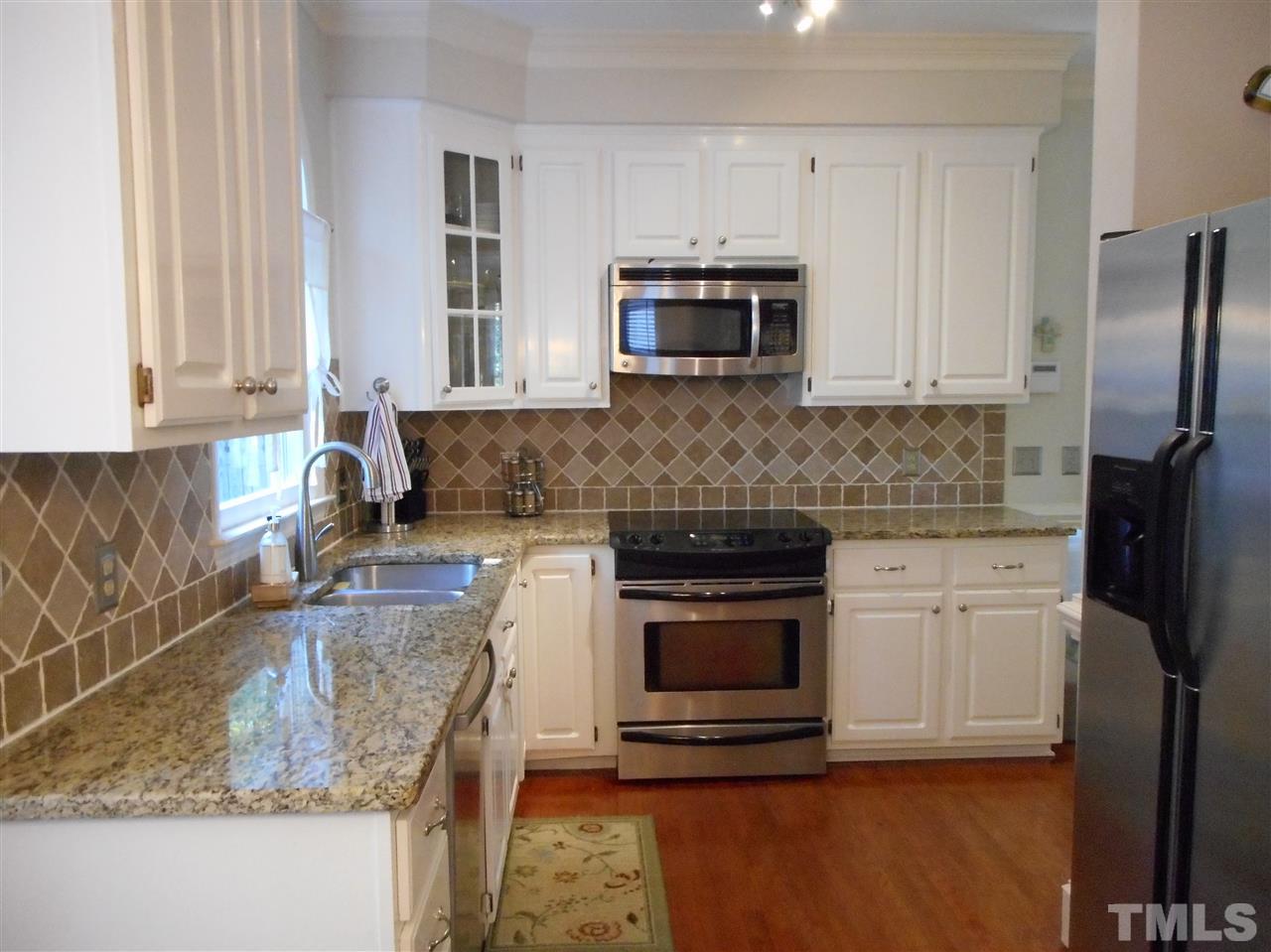 6809 Chasewick Circle Raleigh, NC 27615 - Photo 8 of 23 Looking from the breakfast nook, enjoy the updated kitchen with beautiful granite counters, hardwood floors, and stainless appliances.