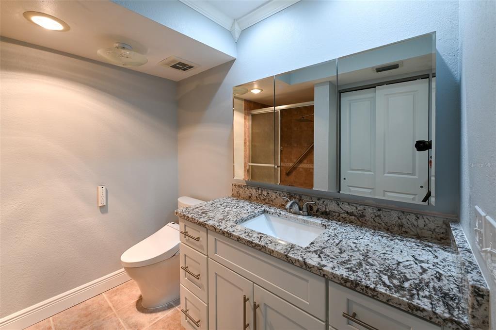 350 Boca Ciega Point Boulevard St. Petersburg, FL 33708 - Photo 17 of 32 a bathroom with a granite countertop sink a toilet and mirror